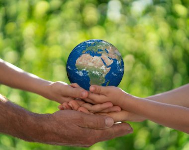 Üç boyutlu gezegeni yeşil bulanık arka plana karşı elinde tutan aile. Dünya bahar tatili konsepti. Bu görüntünün elementleri NASA tarafından desteklenmektedir