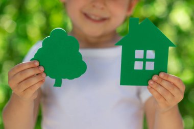 İlkbahar yeşili arka planda çevre evini elinde tutan çocuk. Gayrimenkul ve Dünya Günü konsepti