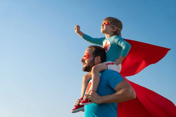 超级英雄的家人在户外玩得很开心父亲和儿子在蓝天的背景下玩耍 想象力和自由的概念 — 图库照片