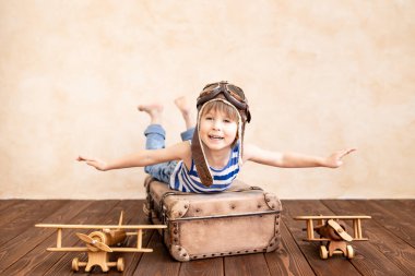 Evde oynayan mutlu çocuk. Gülümseyen çocuk yaz tatili ve seyahat hayali kuruyor. Hayal gücü ve özgürlük kavramı