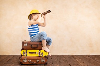 Evde oynayan mutlu çocuk. Gülümseyen çocuk yaz tatili ve seyahat hayali kuruyor. Hayal gücü ve özgürlük kavramı