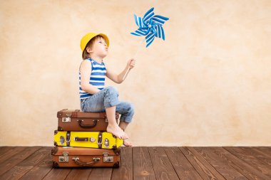 Evde oynayan mutlu çocuk. Gülümseyen çocuk yaz tatili ve seyahat hayali kuruyor. Hayal gücü ve özgürlük kavramı