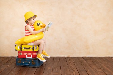 Evde oynayan mutlu çocuk. Gülümseyen çocuk yaz tatili ve seyahat hayali kuruyor. Hayal gücü ve özgürlük kavramı