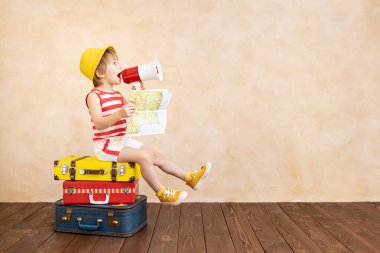 Evde oynayan mutlu çocuk. Gülümseyen çocuk yaz tatili ve seyahat hayali kuruyor. Hayal gücü ve özgürlük kavramı