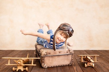 Evde oynayan mutlu çocuk. Gülümseyen çocuk yaz tatili ve seyahat hayali kuruyor. Hayal gücü ve özgürlük kavramı