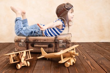 Evde oynayan mutlu çocuk. Gülümseyen çocuk yaz tatili ve seyahat hayali kuruyor. Hayal gücü ve özgürlük kavramı