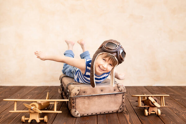 Счастливый ребенок играет дома. Улыбающийся ребенок мечтает о летних каникулах и путешествиях. Воображение и свобода