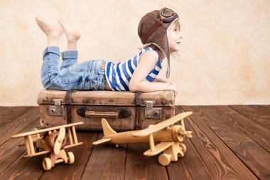 Evde oynayan mutlu çocuk. Gülümseyen çocuk yaz tatili ve seyahat hayali kuruyor. Hayal gücü ve özgürlük kavramı