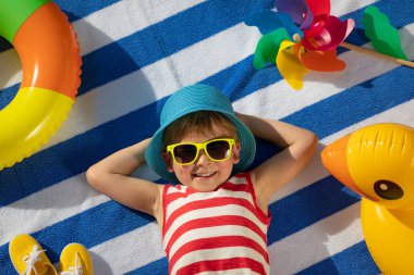 Dışarıda çizgili havlunun üzerinde yatan mutlu çocuk. Çocuk portresi. Gülen komik bebek. Yaz tatili kavramı