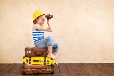 Evde oynayan mutlu çocuk. Gülümseyen çocuk yaz tatili ve seyahat hayali kuruyor. Hayal gücü ve özgürlük kavramı