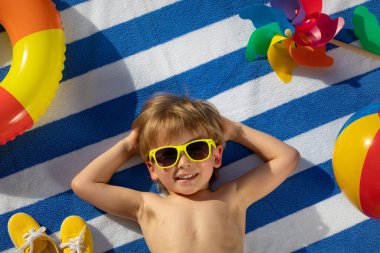 Dışarıda çizgili havlunun üzerinde yatan mutlu çocuk. Çocuk portresi. Gülen komik bebek. Yaz tatili kavramı