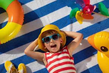 Dışarıda çizgili havlunun üzerinde yatan mutlu çocuk. Çocuk portresi. Gülen komik bebek. Yaz tatili kavramı