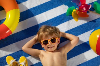 Dışarıda çizgili havlunun üzerinde yatan mutlu çocuk. Çocuk portresi. Gülen komik bebek. Yaz tatili kavramı