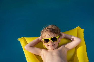 Havuzda yüzen mutlu çocuk. Çocuk yaz tatilinde eğleniyor. Sağlıklı yaşam tarzı kavramı