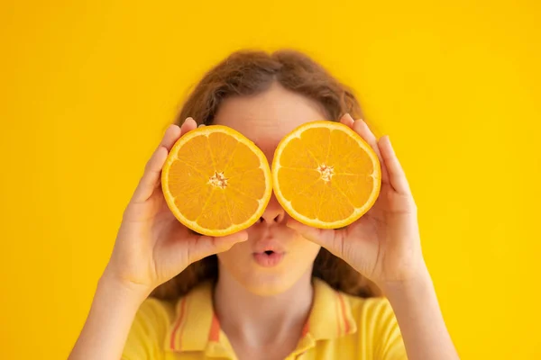拿着橙子半边而不是太阳镜的孩子 黄色背景下令人惊讶的女孩的画像 — 图库照片