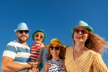 Mutlu bir aile mavi gökyüzü geçmişine karşı eğleniyor. Anne, baba, kız ve oğul yaz tatilinde.