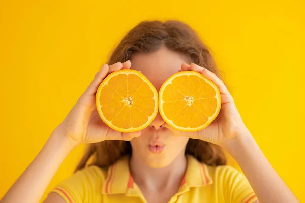 拿着橙子半边而不是太阳镜的孩子 黄色背景下令人惊讶的女孩的画像 — 图库照片