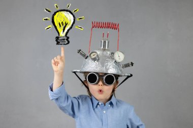 Akıllı çocuk iş adamı gibi davranıyor. Ampullü kask takan komik çocuk. Şaşkın çocuğun bir fikri var. Eğitim, yapay zeka ve iş fikri