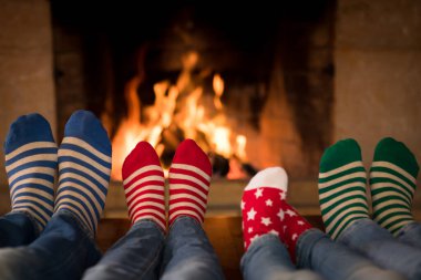 Noel çoraplı aile şöminenin yanında. Anne, baba ve çocuklar birlikte eğleniyorlar. İnsanlar evde dinleniyor. Kış tatili Xmas ve Yeni Yıl konsepti