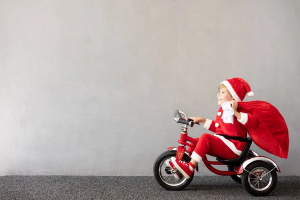 クリスマスの衣装を着た幸せな子供 子供用自転車 面白い子は赤い袋を持っている 子供は冬にアウトドアを楽しんでいます クリスマス休暇のコンセプト — ストック写真
