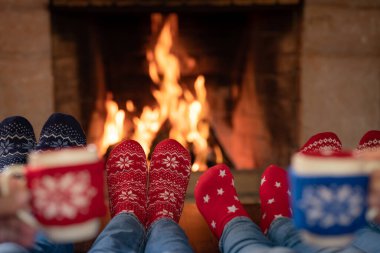 Noel çoraplı aile şöminenin yanında. Anne, baba ve çocuklar birlikte eğleniyorlar. İnsanlar evde dinleniyor. Kış tatili Xmas ve Yeni Yıl konsepti
