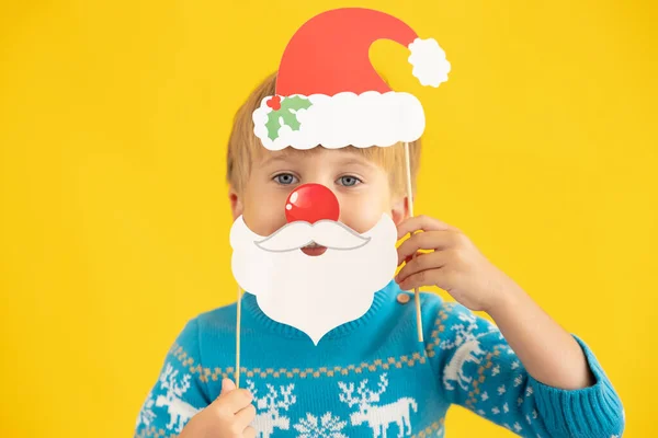 快乐的孩子拿着圣诞老人的帽子和胡子 以黄色为背景的小孩有趣的孩子在室内玩耍 圣诞假期的概念 — 图库照片
