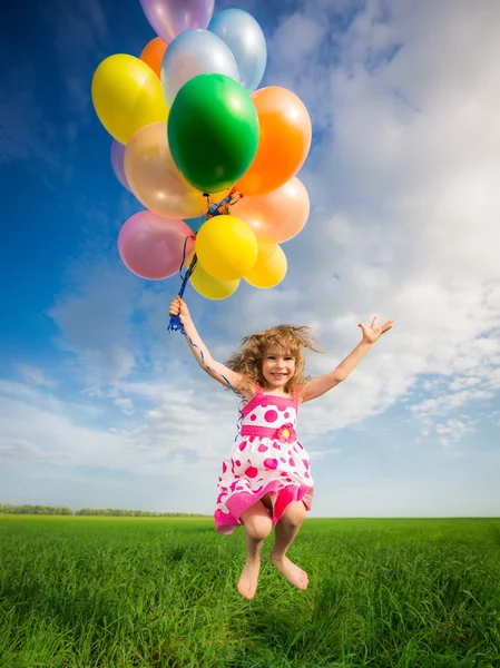 Enfant avec des ballons jouets dans le champ de printemps — Photo