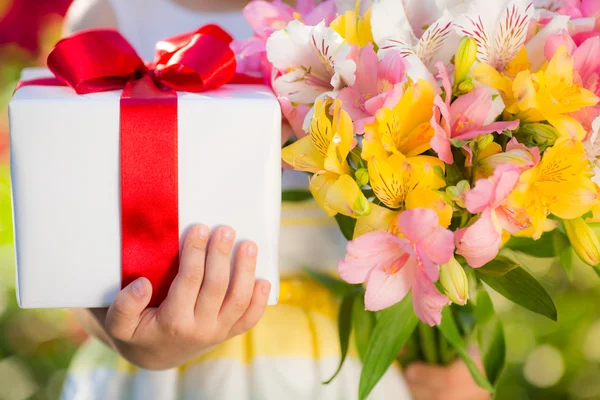 Caixa de presente e flores nas mãos — Fotografia de Stock