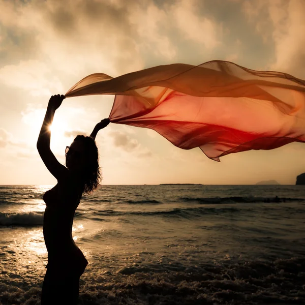 Silhouette einer jungen Frau, die am Strand springt — Stockfoto