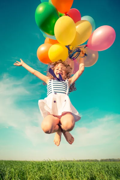 Child with toy balloons in spring field — Stock Photo, Image