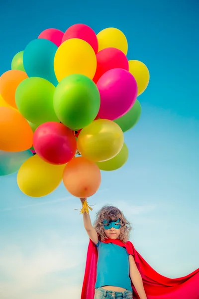 Superbohater z zabawkami balony wiosna pole — Zdjęcie stockowe