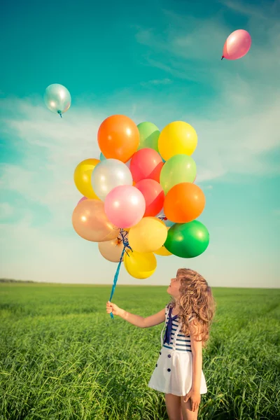 Bambino con palloncini giocattolo in campo primaverile — Foto Stock