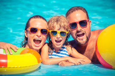 Happy family playing in swimming pool clipart