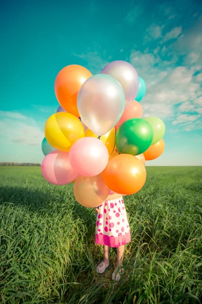 Niño con globos en campo de primavera —  Fotos de Stock