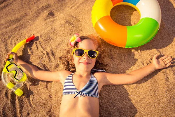 Criança feliz deitada na praia — Fotografia de Stock