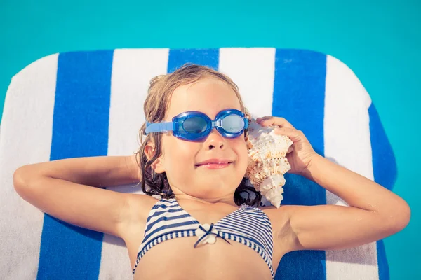 Criança feliz ouvir a concha na praia — Fotografia de Stock