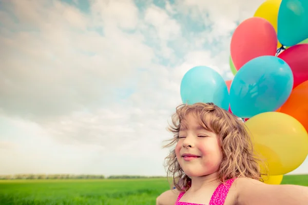 Child with balloons in spring field — Stock Photo, Image