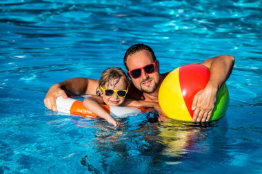 Çocuk ve yüzme havuzunda oynayan baba