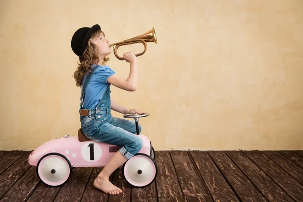 Kind spielt mit Spielzeugauto und Trompete — Stockfoto