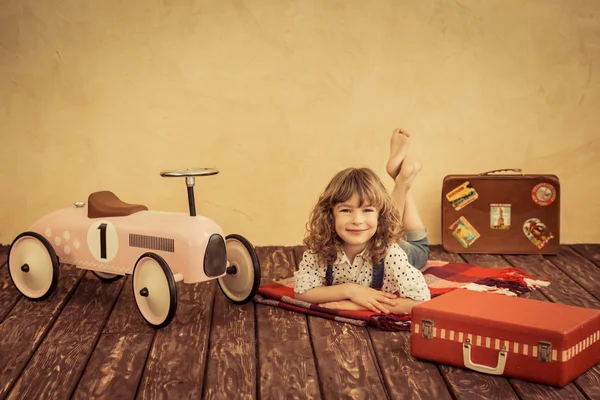 Niño jugando con coche de juguete y maletas — Foto de Stock
