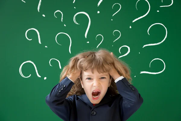 Angry school kid  with question marks — Stock Photo, Image