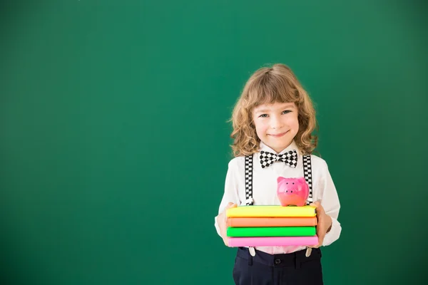 Schooljong geitje met boeken en moneybox — Stockfoto