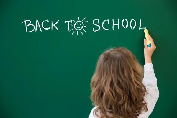 Школьник пишет "Назад в школу" — стоковое фото