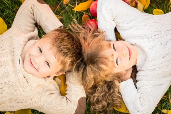 Дети, лежащие на осенних листьях — стоковое фото
