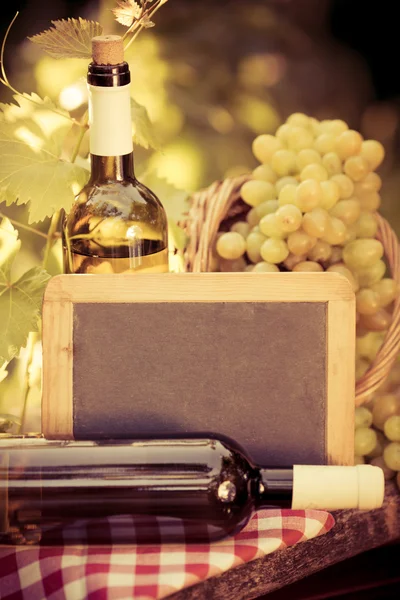 Blackboard , wine bottle and grapes of vine — Stock Photo, Image