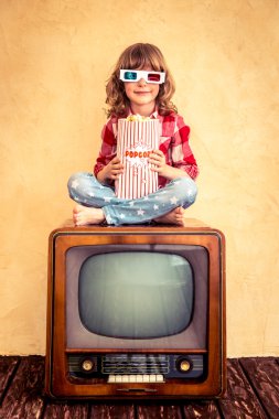 Retro televizyonda oturan ve patlamış mısır yemek çocuk.