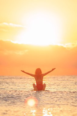 Genç bir kadın yaz tatilinde denize karşı kürek çekerek ayakta yürüyor. Güzel bir kadın denize ve gündoğumuna karşı kürek çekiyor. Özgürlük ve hayal gücü kavramı