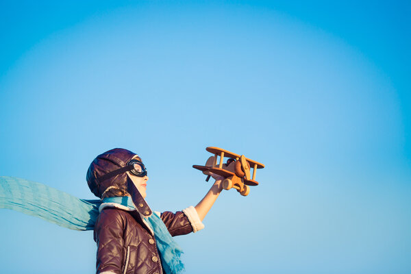 Счастливый ребенок играет с игрушечным самолетом
