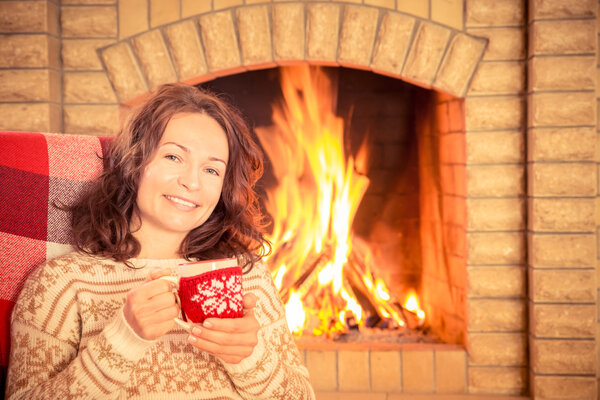 Woman with cup near fireplace