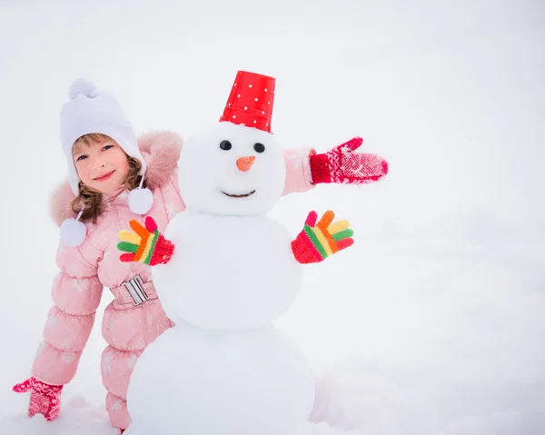 Enfant et bonhomme de neige en hiver — Photo